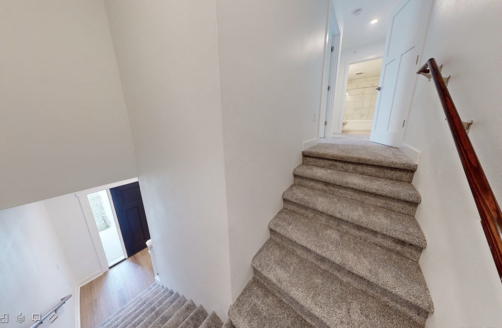 a look down the stairs of a home with white walls and carpet