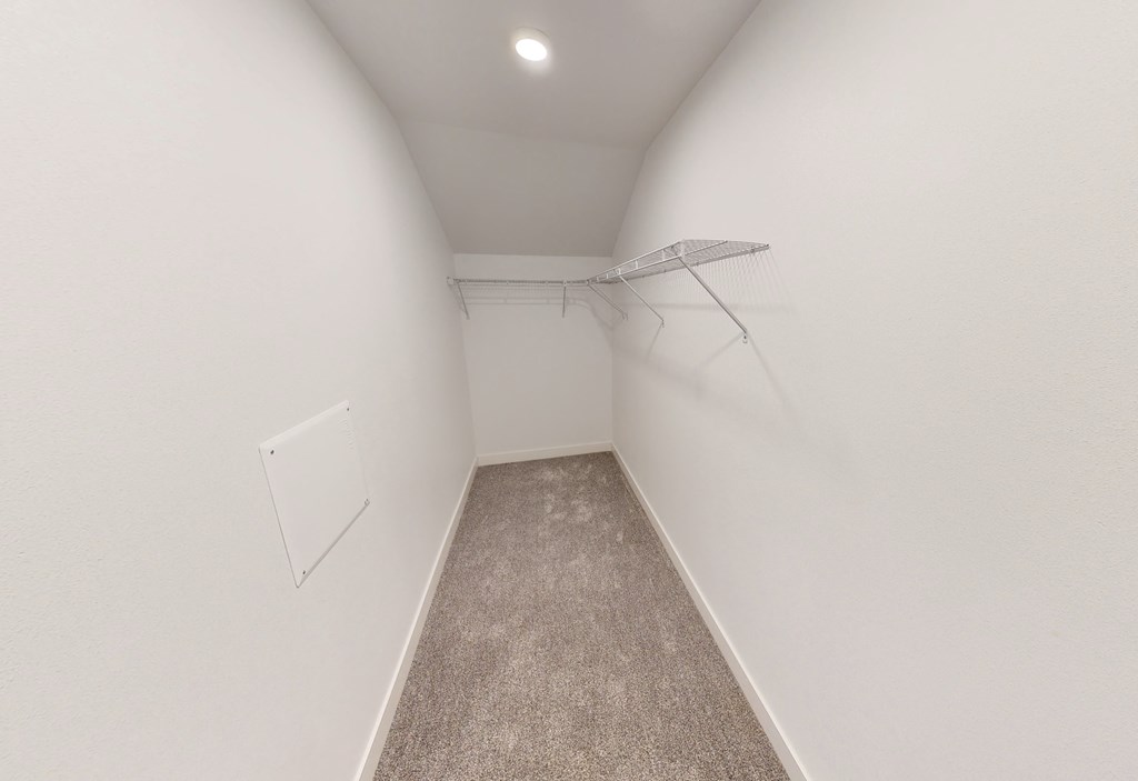 a room with white walls and a closet with a wire rack on the wall