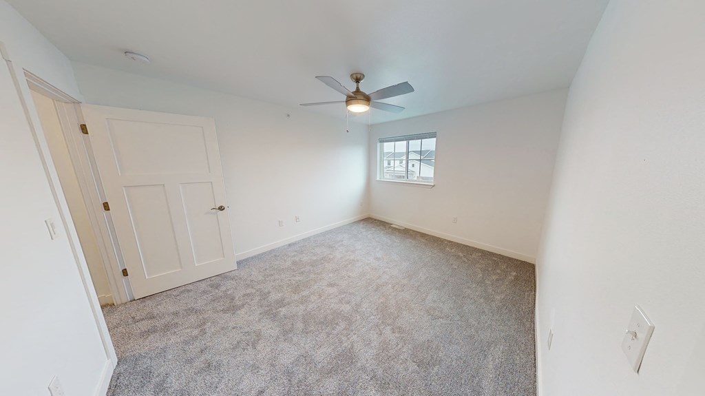 an empty living room with a ceiling fan and a window