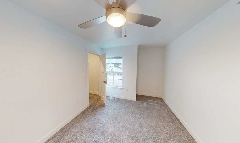 an empty room with a ceiling fan and a window