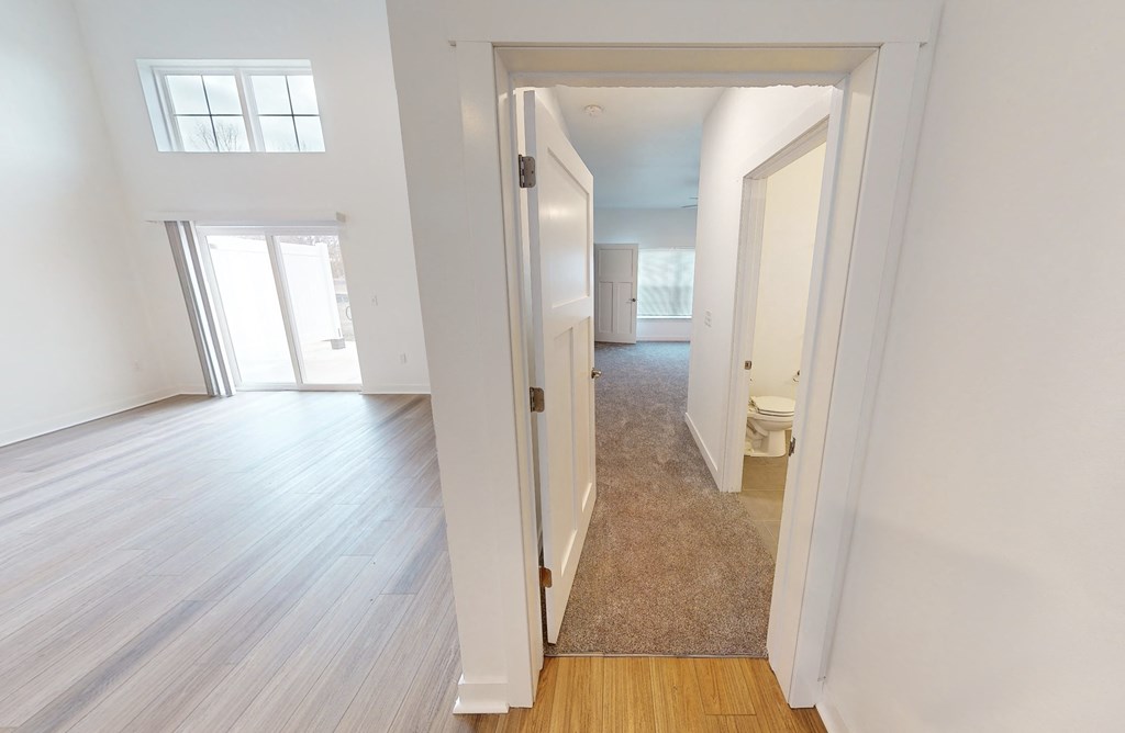 an empty living room and hallway with white walls and wood floors