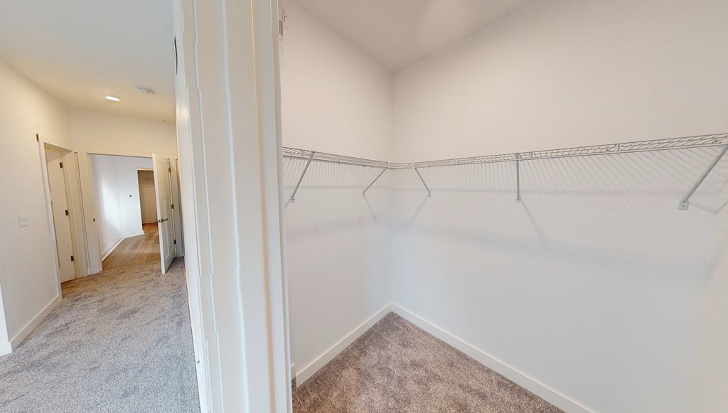 an empty closet in a home with white walls and carpeting