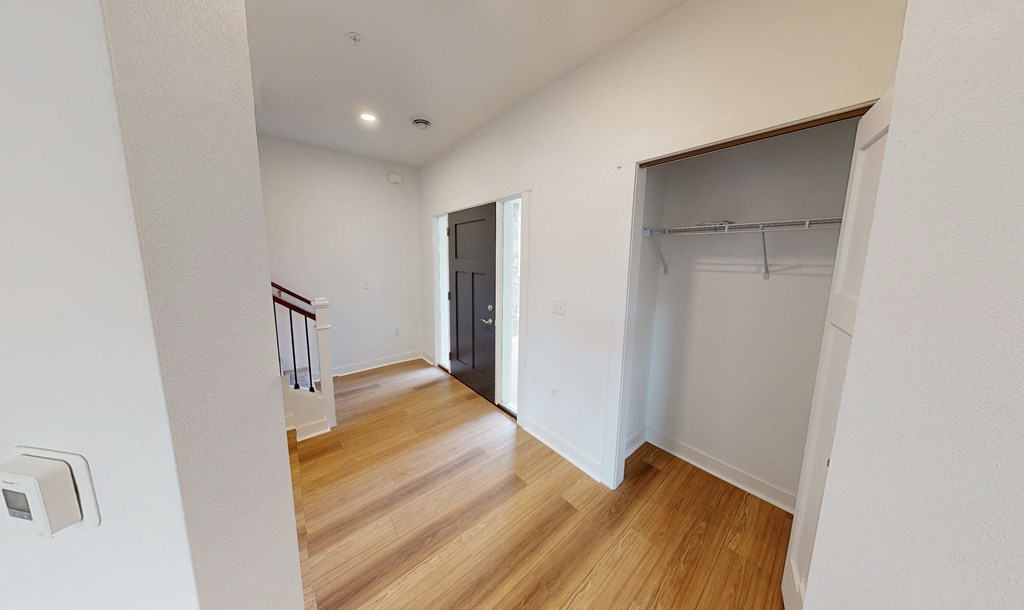 a bedroom with a door to a closet and a hallway with wood flooring