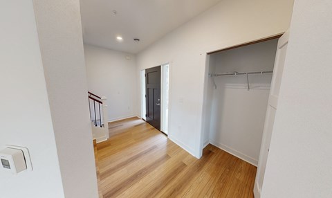 a bedroom with a door to a closet and a hallway with wood flooring