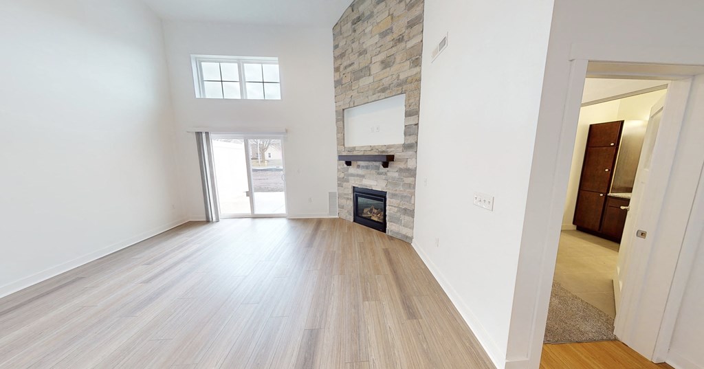 an empty living room with a fireplace and wood flooring