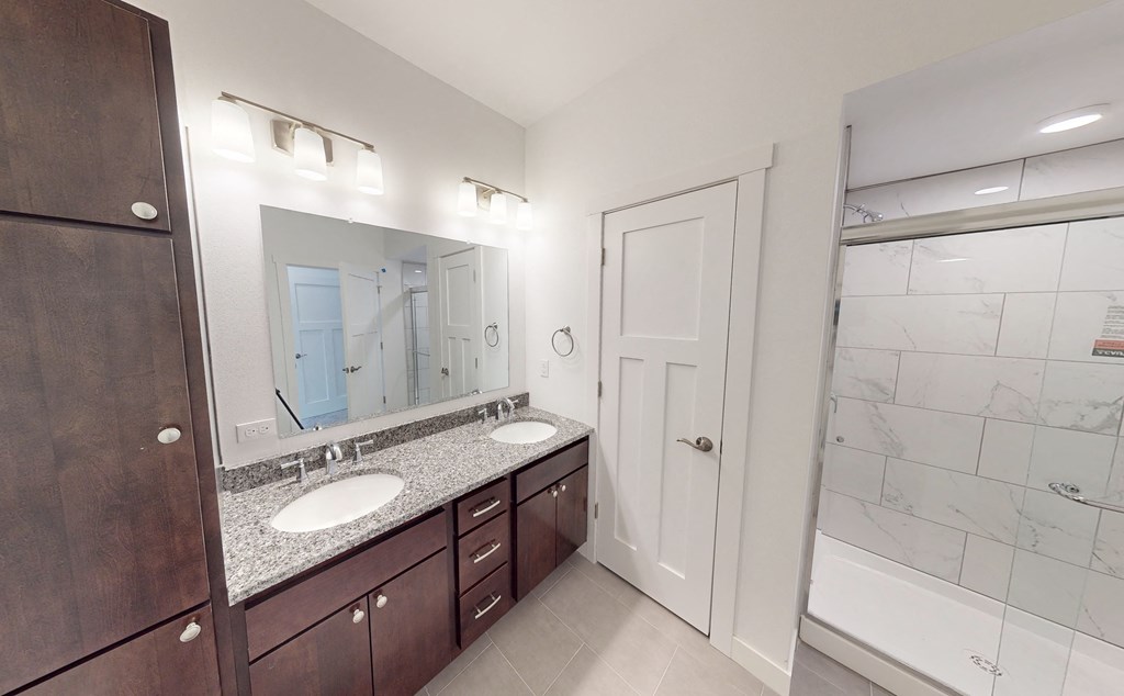 a bathroom with two sinks and a shower and a mirror