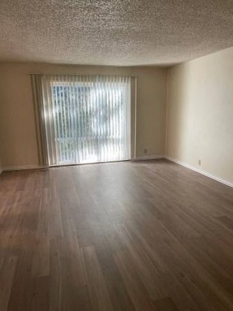 an empty living room with wood floors and a window