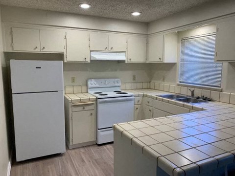 an empty kitchen with white appliances and white cabinets