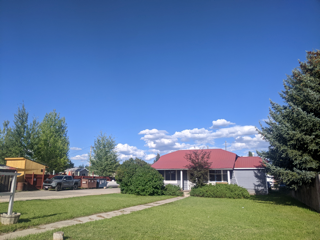 a house with a red roof and a lawn and trees