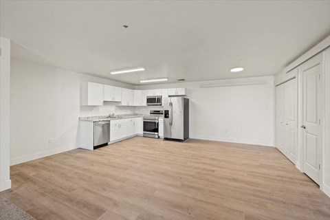 an empty kitchen with white cabinets and stainless steel appliances
