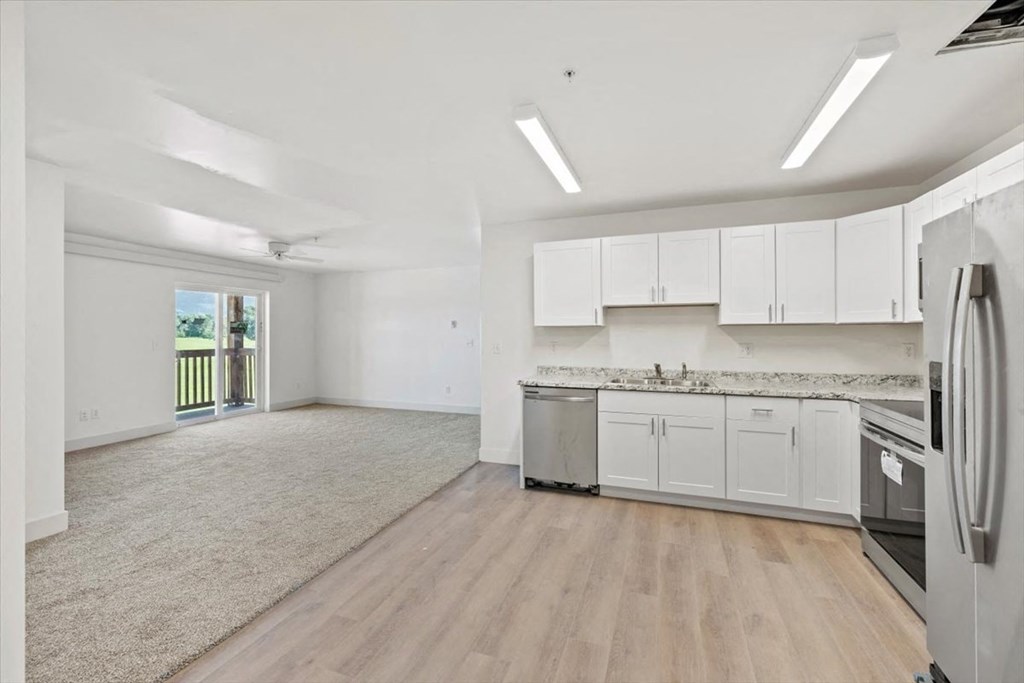 an empty kitchen with white cabinets and stainless steel appliances