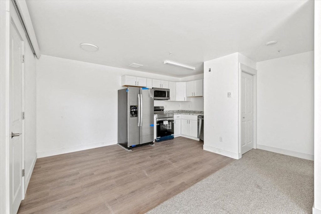a renovated kitchen with white cabinets and a stainless steel refrigerator