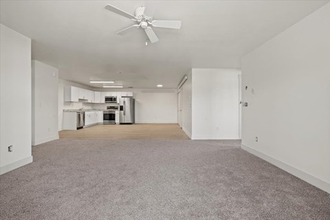 an empty living room and kitchen with a ceiling fan