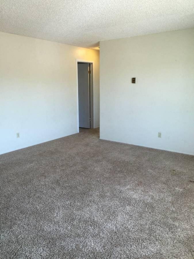 the living room of an empty apartment with white walls and carpet
