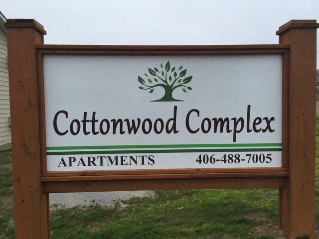 a sign for cottonwood complex apartments with a tree on it