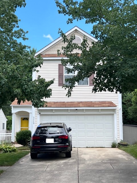 A black car is parked in front of a white garage.