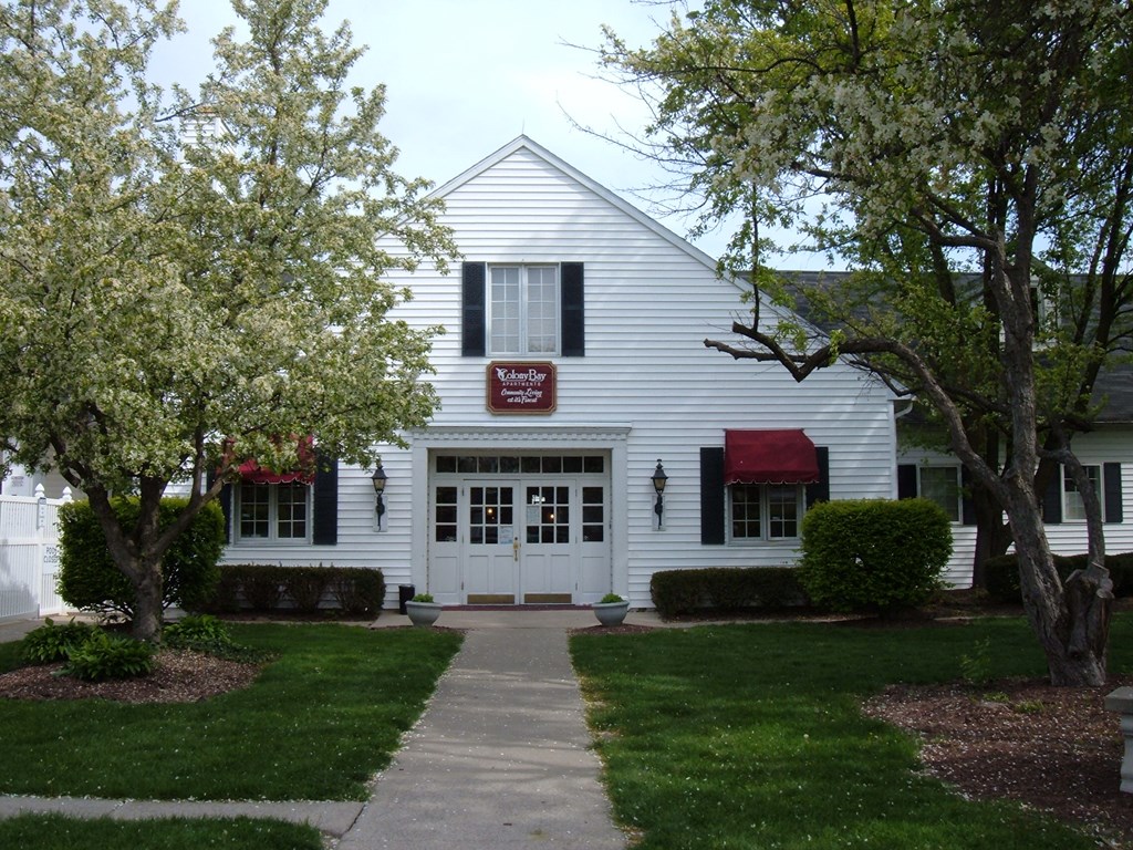 a white house with a sidewalk and trees in front of it
