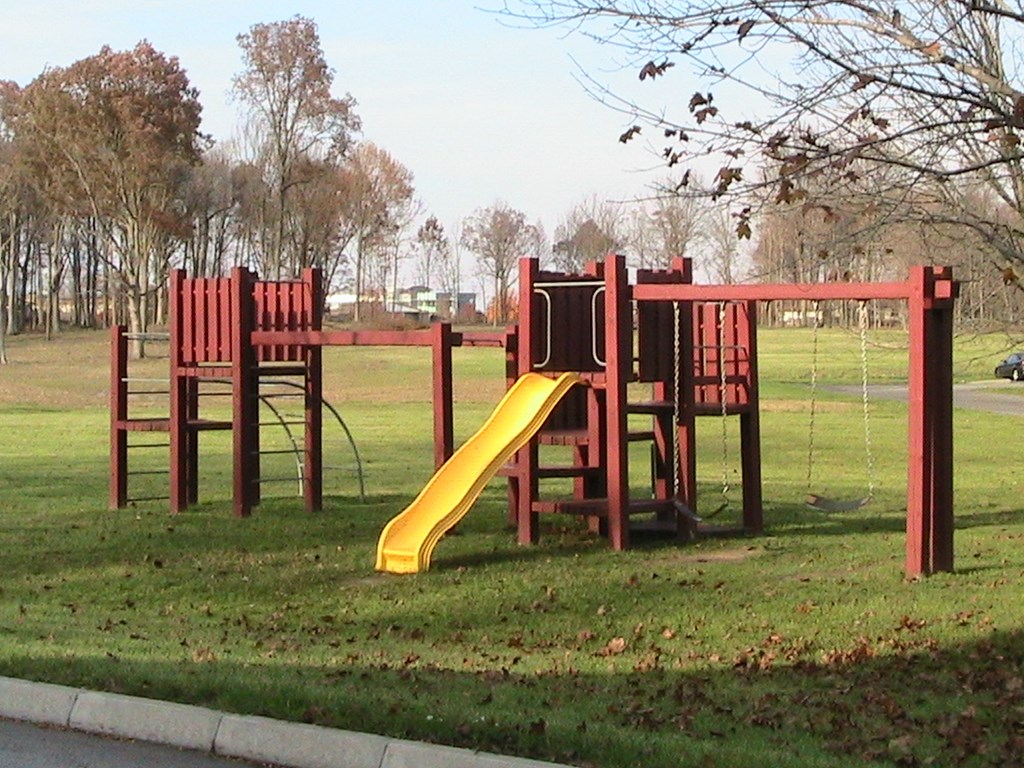 a playground with a yellow slide in a park
