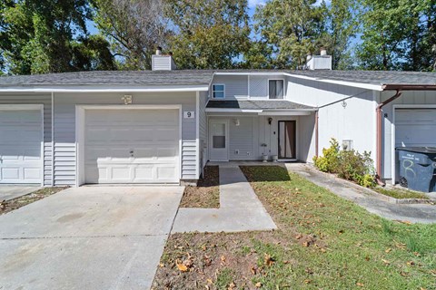A white house with a grey roof and a garage door.