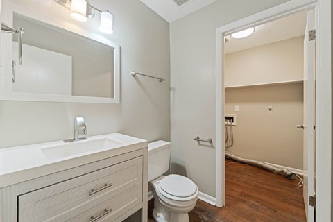 A white bathroom with a toilet, sink, and mirror.