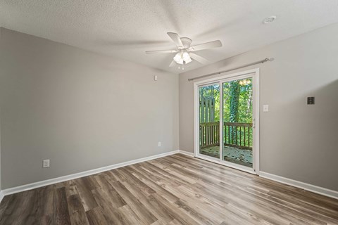 A room with a ceiling fan and sliding glass doors leading to a deck.
