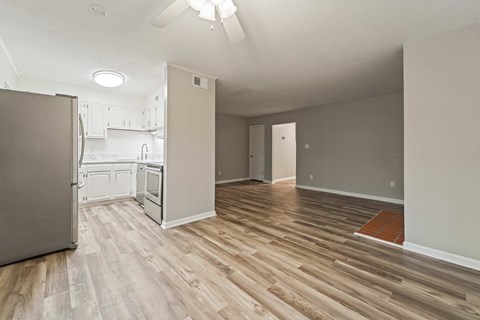 A kitchen with a refrigerator and wooden floors.