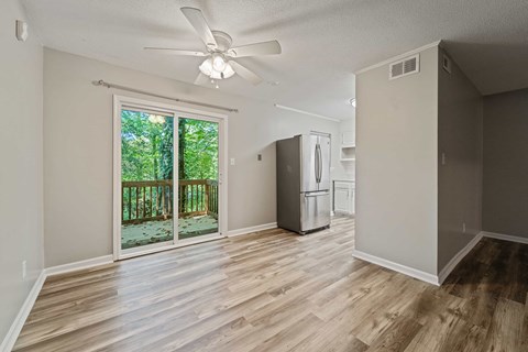 A room with a ceiling fan and a refrigerator.