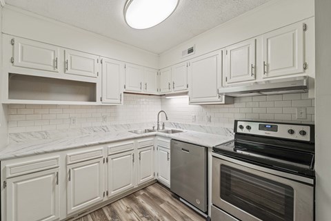 A kitchen with white cabinets and a black stove top oven.