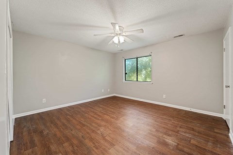 Empty room with wood flooring and a ceiling fan.