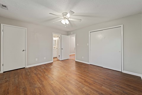A room with a ceiling fan and wooden floors.