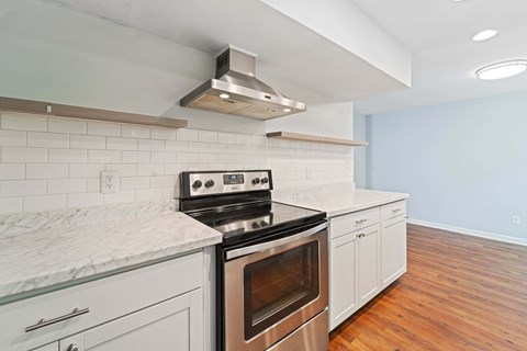 A modern kitchen with a stove top oven and white cabinets.