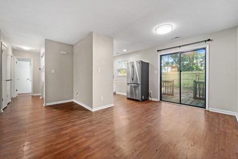 A spacious room with wooden floors and a refrigerator.