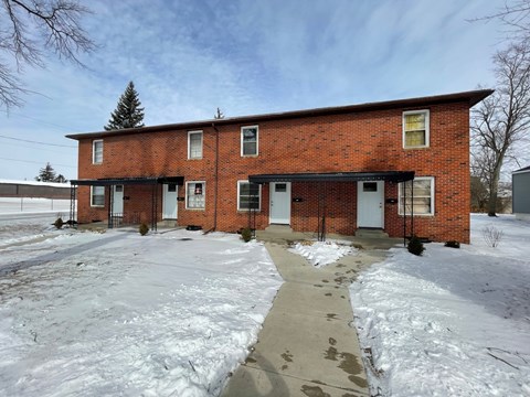 A red brick house with a snow-covered ground.