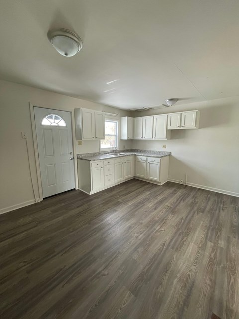A kitchen with white cabinets and a wooden floor.