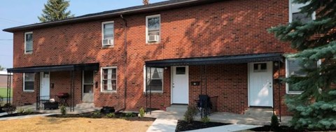 A red brick house with a white door and windows.