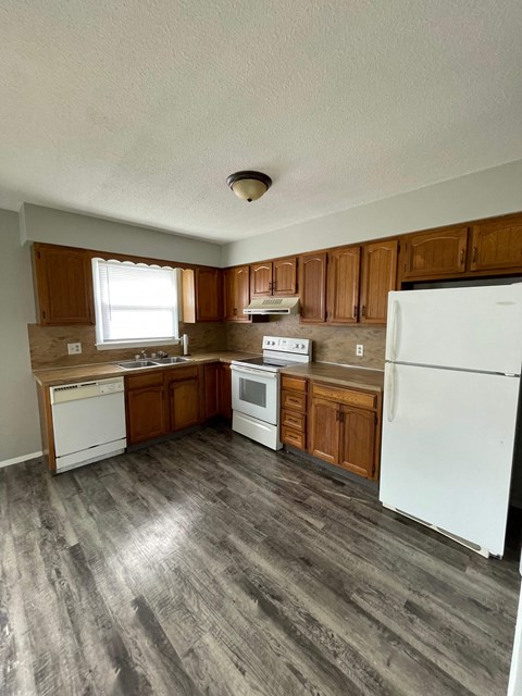 an empty kitchen with white appliances and wooden cabinets