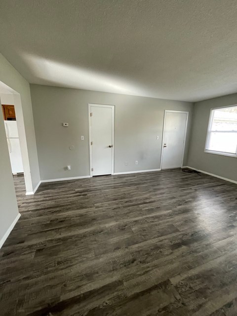 an empty living room with wooden floors and white walls