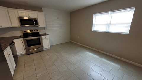 an empty kitchen with white cabinets and stainless steel appliances