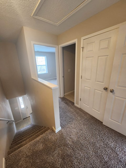 a view of the hallway from the top of the stairs looking down at the door