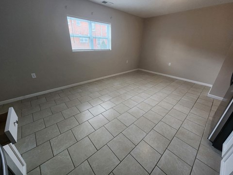 a empty living room with a window and a tiled floor