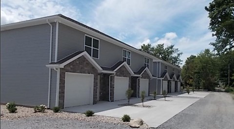a row of gray houses with white doors and a sidewalk
