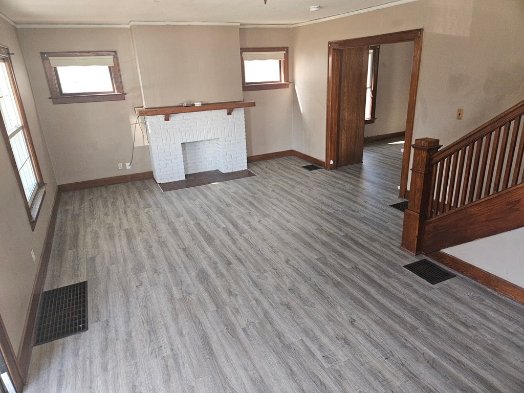 an empty living room with a wooden floor and a fireplace