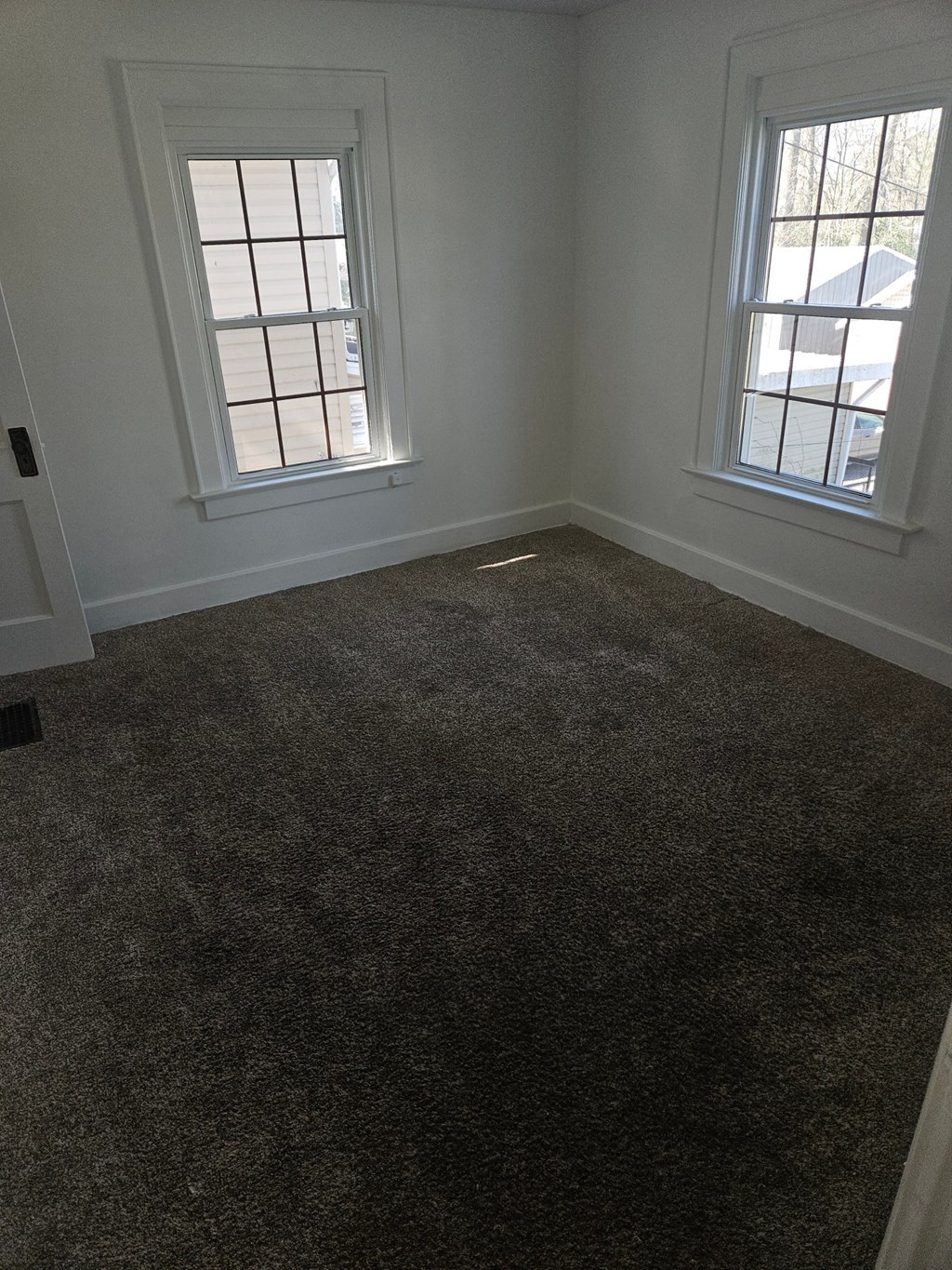 an empty room with a carpeted floor and two windows