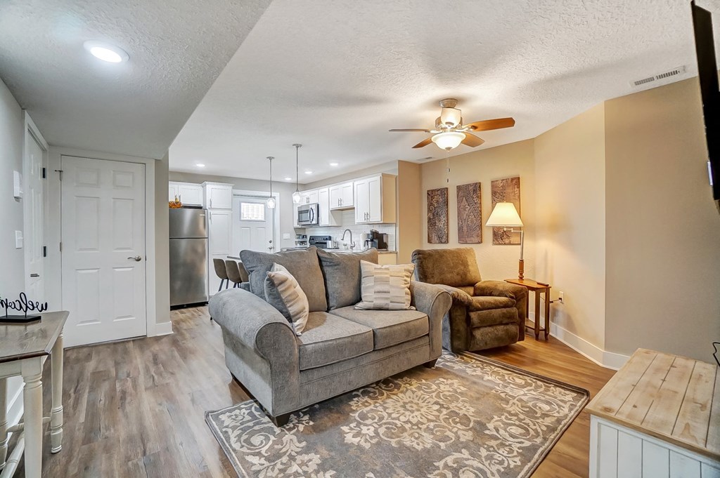 a living room and kitchen with a couch and a ceiling fan