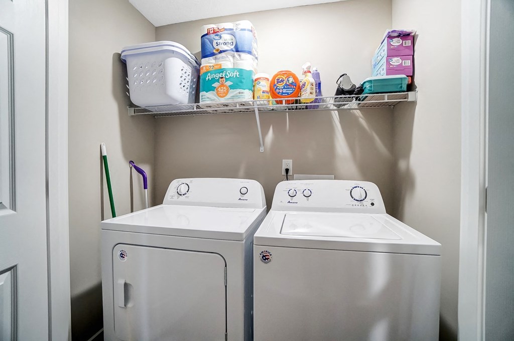 a washer and dryer in a laundry room with a shelf above them