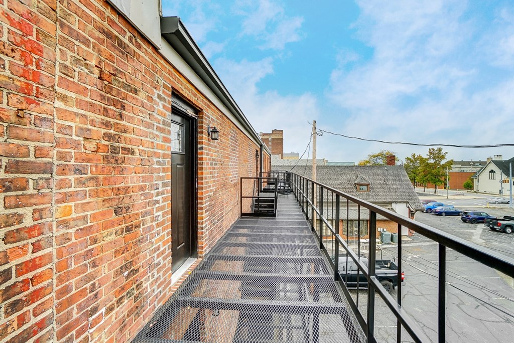 the balcony has a view of the city and a brick building