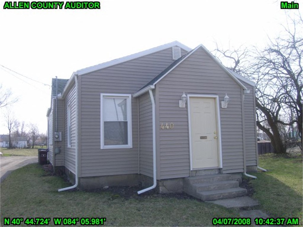the front of a small gray house with a white door