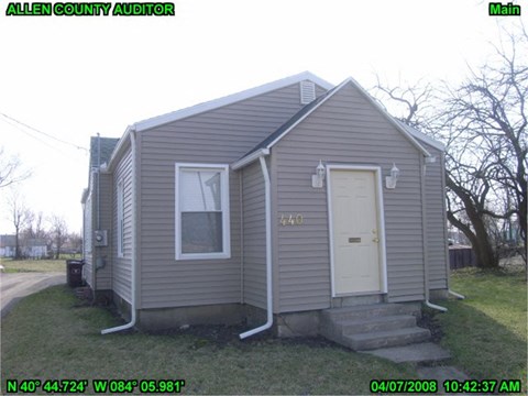 the front of a small gray house with a white door