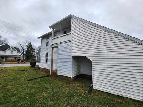 the side of a white house with a garage door open