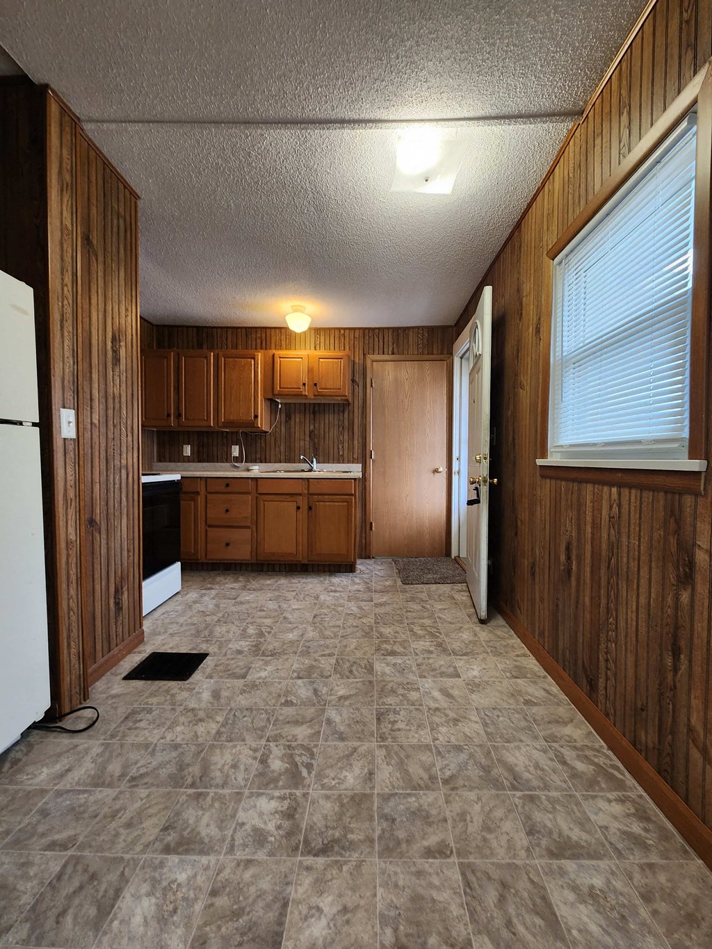 an empty kitchen with wooden cabinets and a white refrigerator